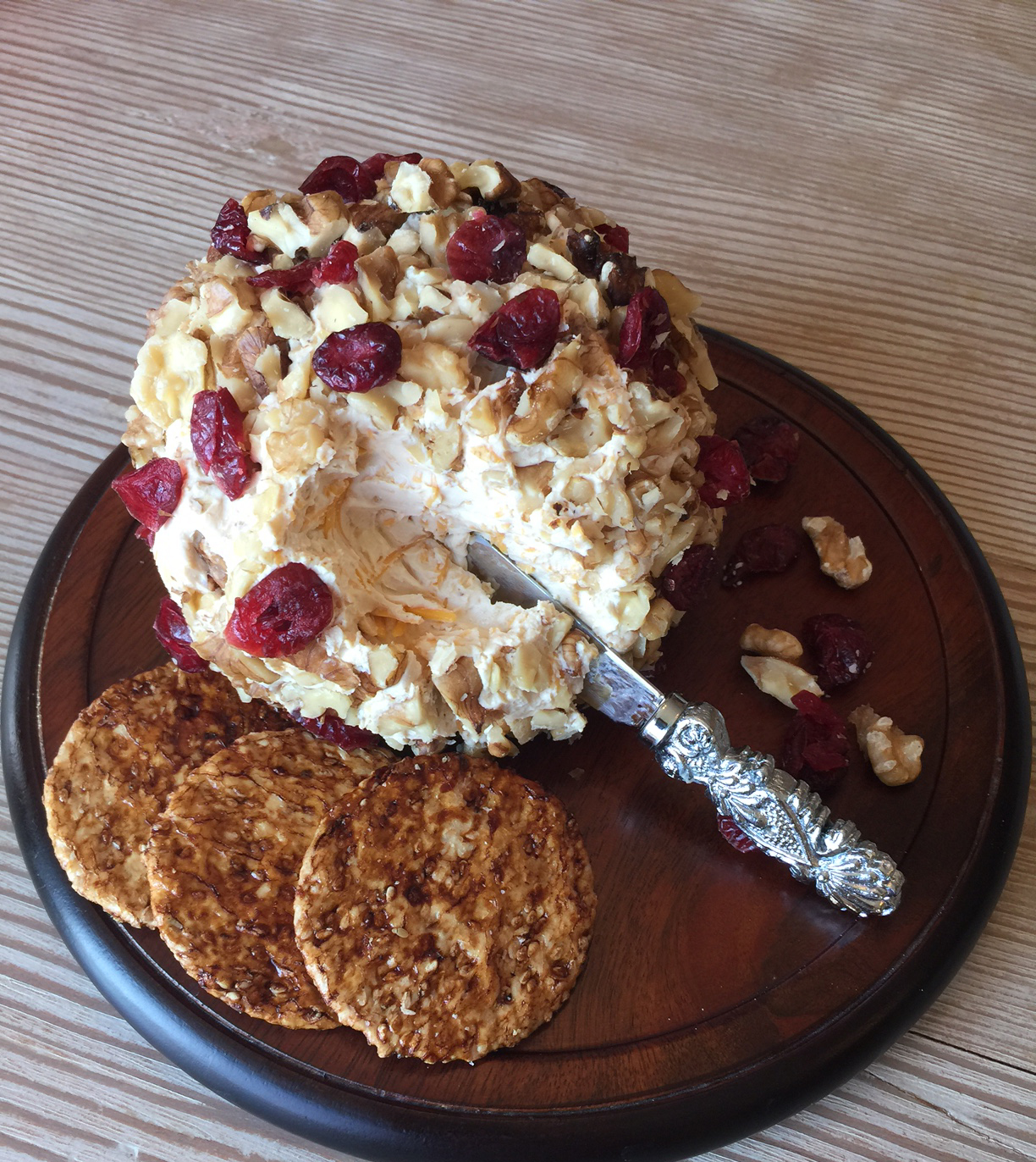 Orange Cranberry Cheese Ball with crackers on a cheese board with a knife by San-J