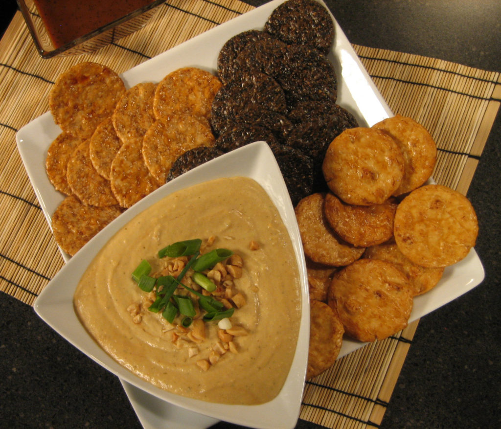A platter of crackers with San-J Asian hummus in a bowl